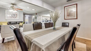 A dining area with a table set for six, surrounded by leather chairs, a vase with flowers, and framed artwork on the walls.