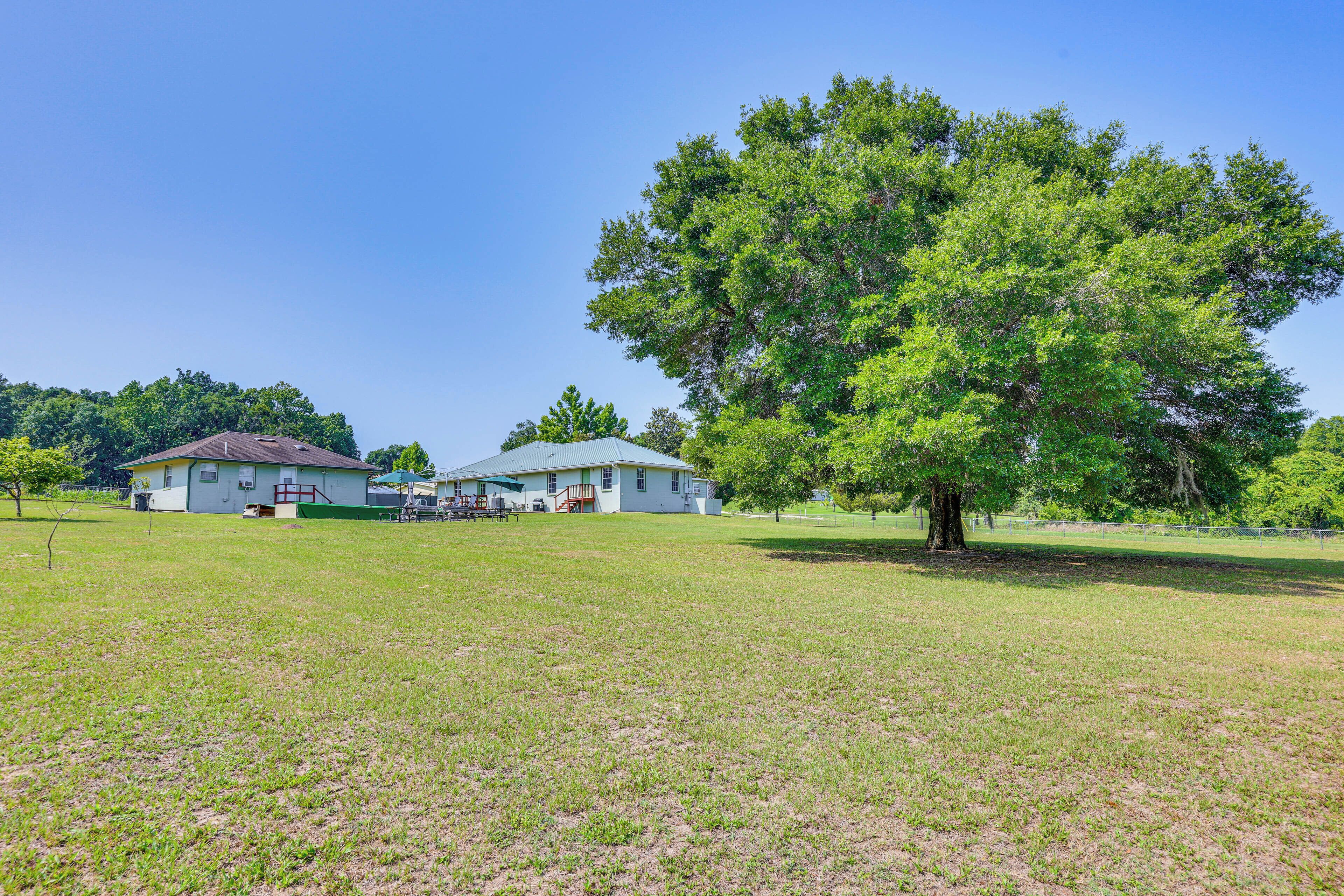 A grassy field with two white buildings and a large tree.