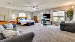 A bedroom with a bed, a desk, a chair, a sofa, and a TV.