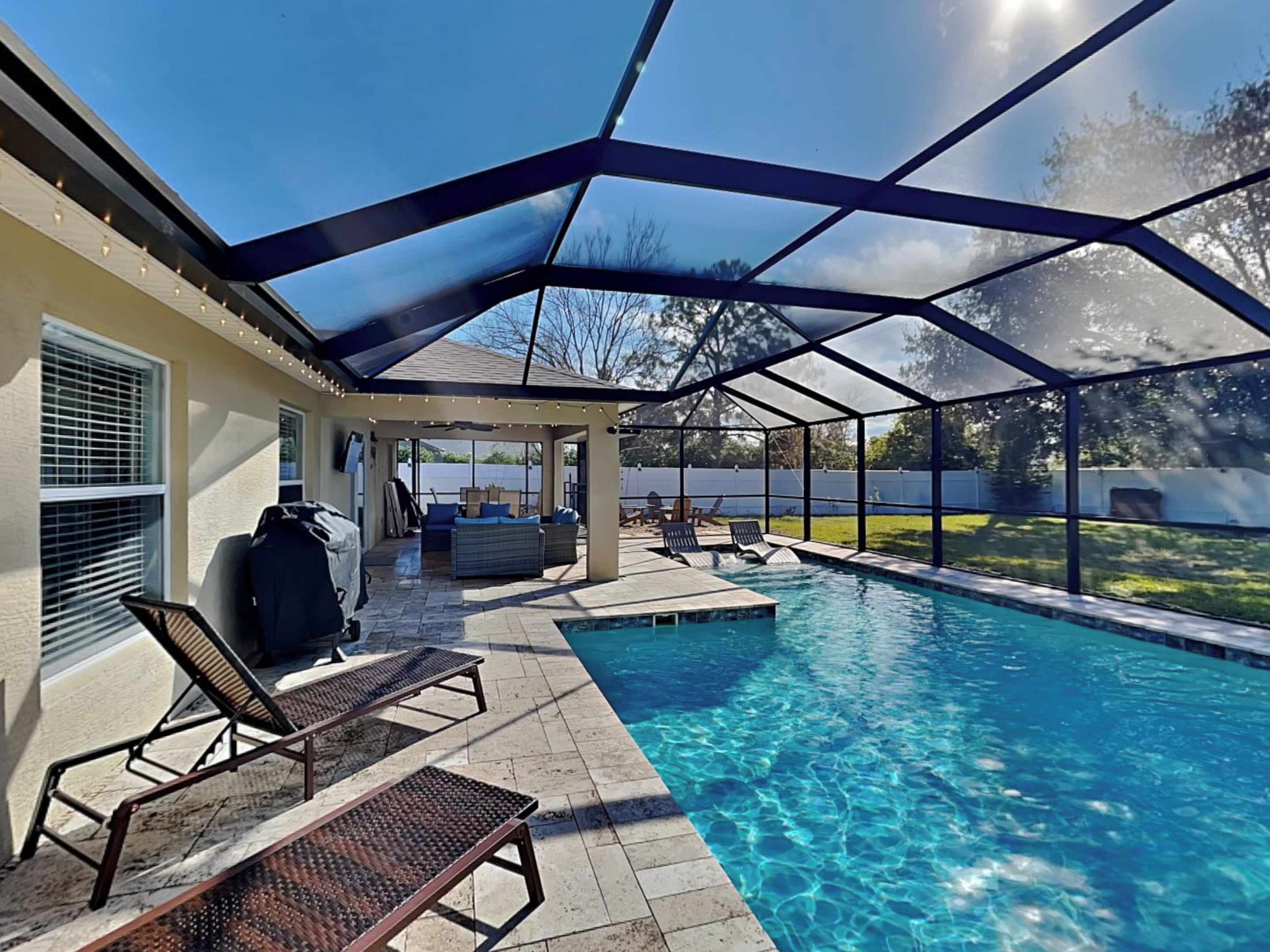 Un espace extérieur abrité avec une piscine, des chaises longues et un barbecue.