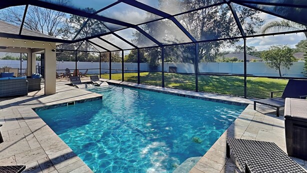 Une piscine extérieure couverte, avec une eau d’un bleu limpide, entourée de chaises longues et d’un espace patio.