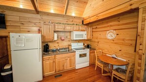Eine kleine Küche mit Holzschränken, einem Kühlschrank, einer Mikrowelle, einem Herd und einem Spülbecken.