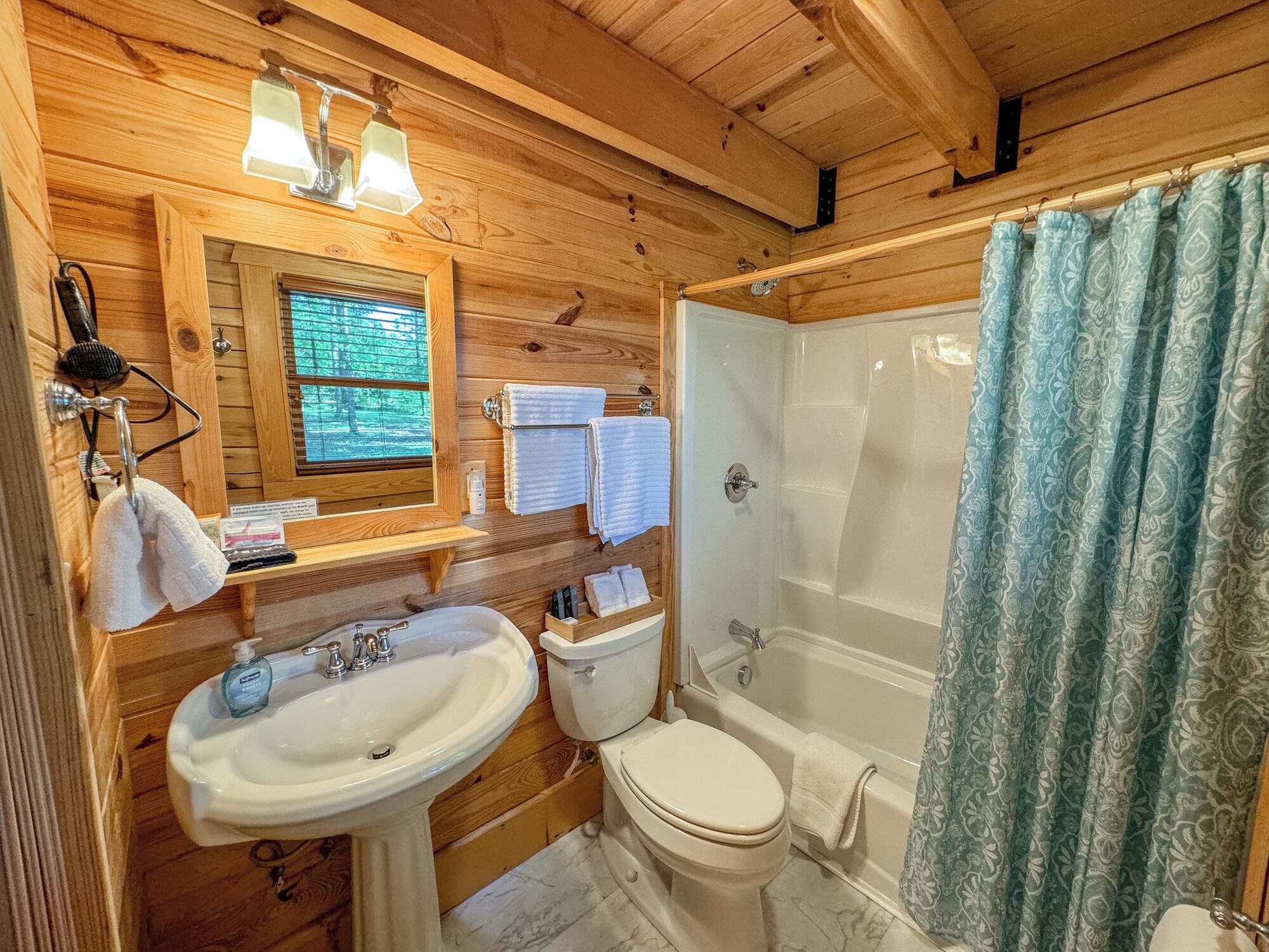 Uma casa de banho de cabana de madeira, com lavatório, sanita e banheira.