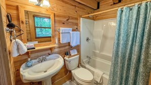 Ein Badezimmer einer Holzhütte mit Waschbecken, Toilette und Badewanne.