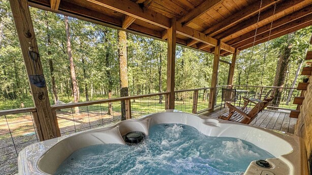 Ein Whirlpool auf einer Holzterrasse mit Blick auf einen Wald.