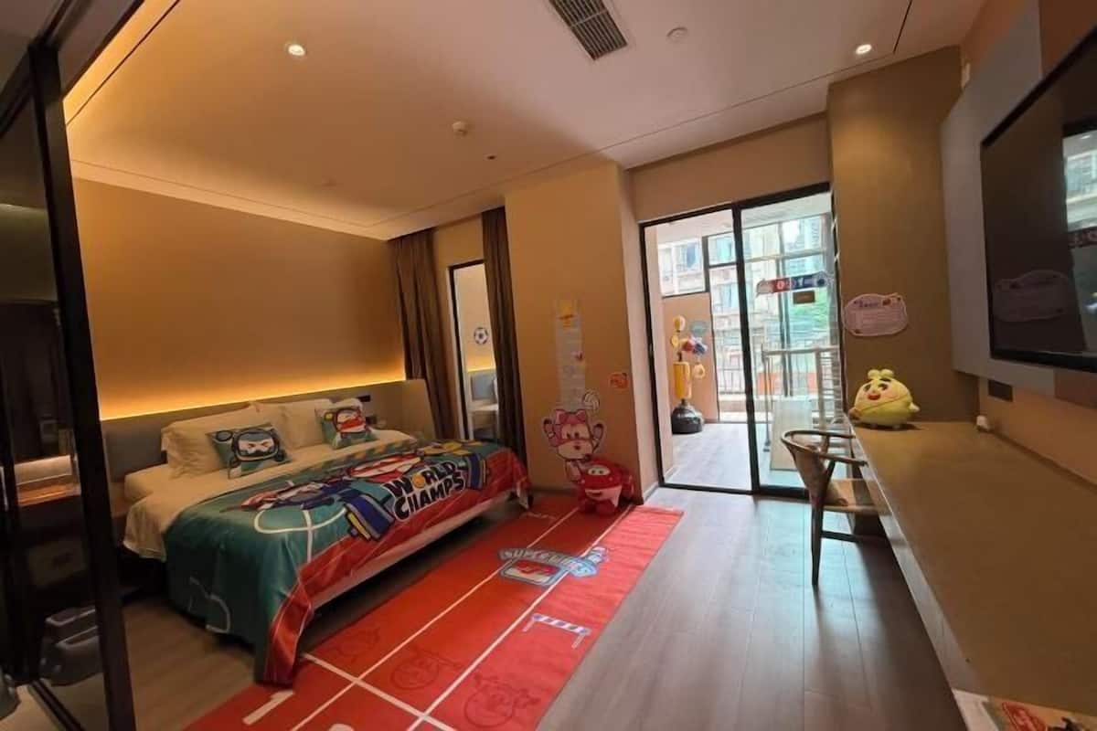 A hotel room with a bed, a desk, a window, and a door.
