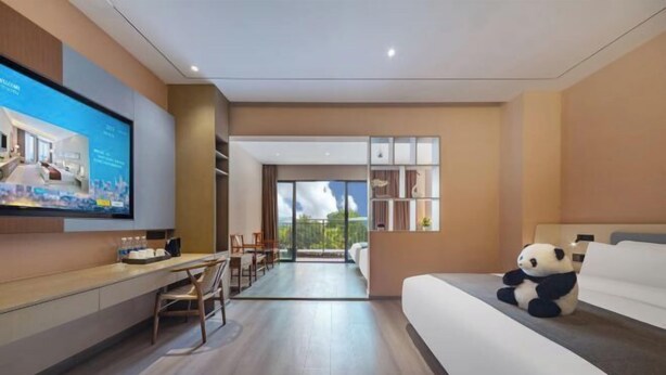 Ein modernes Hotelzimmer mit einem großen Bett, einem Schreibtisch, einem Fernseher und einem Balkon mit Blick.