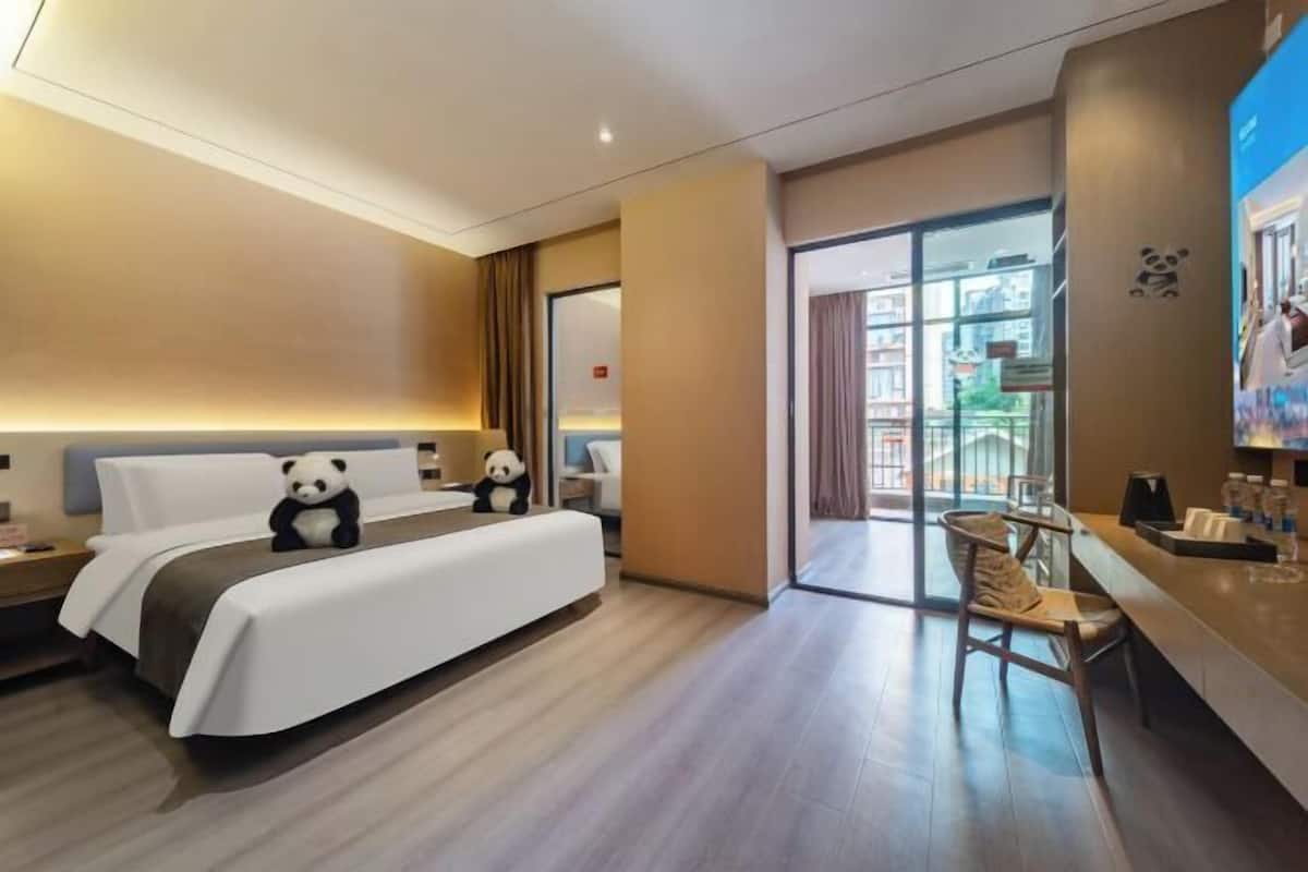 A hotel room with a bed, a desk, a chair, and a large window.