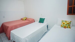 A simple room with two beds, one with a red bedspread and the other with a white bedspread. - POUSADA DOS GIRASSOIS TRANCOSO (Porto Seguro)