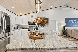 A modern kitchen with granite countertops, stainless steel appliances, and a central island with a wine bottle and glasses.