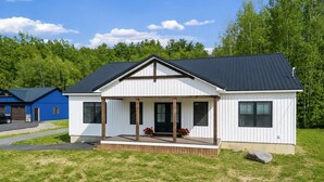 Una casa a un piano con portico, garage e un prato curato.