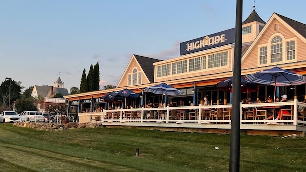 Un ristorante con posti a sedere all'aperto, un cartello con su scritto 'HIGH TIDE' e vista sulla zona circostante.