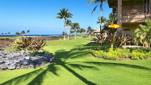 A hotel with a view of the ocean, a well-maintained lawn, and a sign indicating the direction to the hotel.