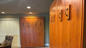 A room with a large wooden wardrobe, a bench, and a door with latches. - Bass Lake luxury cabin with lake views & boat slip (Bass Lake)