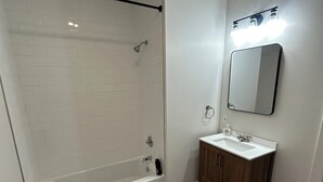 A bathroom with a shower, toilet, sink, and wooden cabinets.