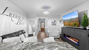 Ein modernes Wohnzimmer mit Kamin, großem Fernseher und Marmorboden.