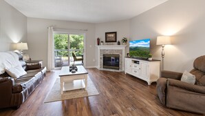 Ein Wohnzimmer mit Kamin, Fernseher und Blick ins Freie.