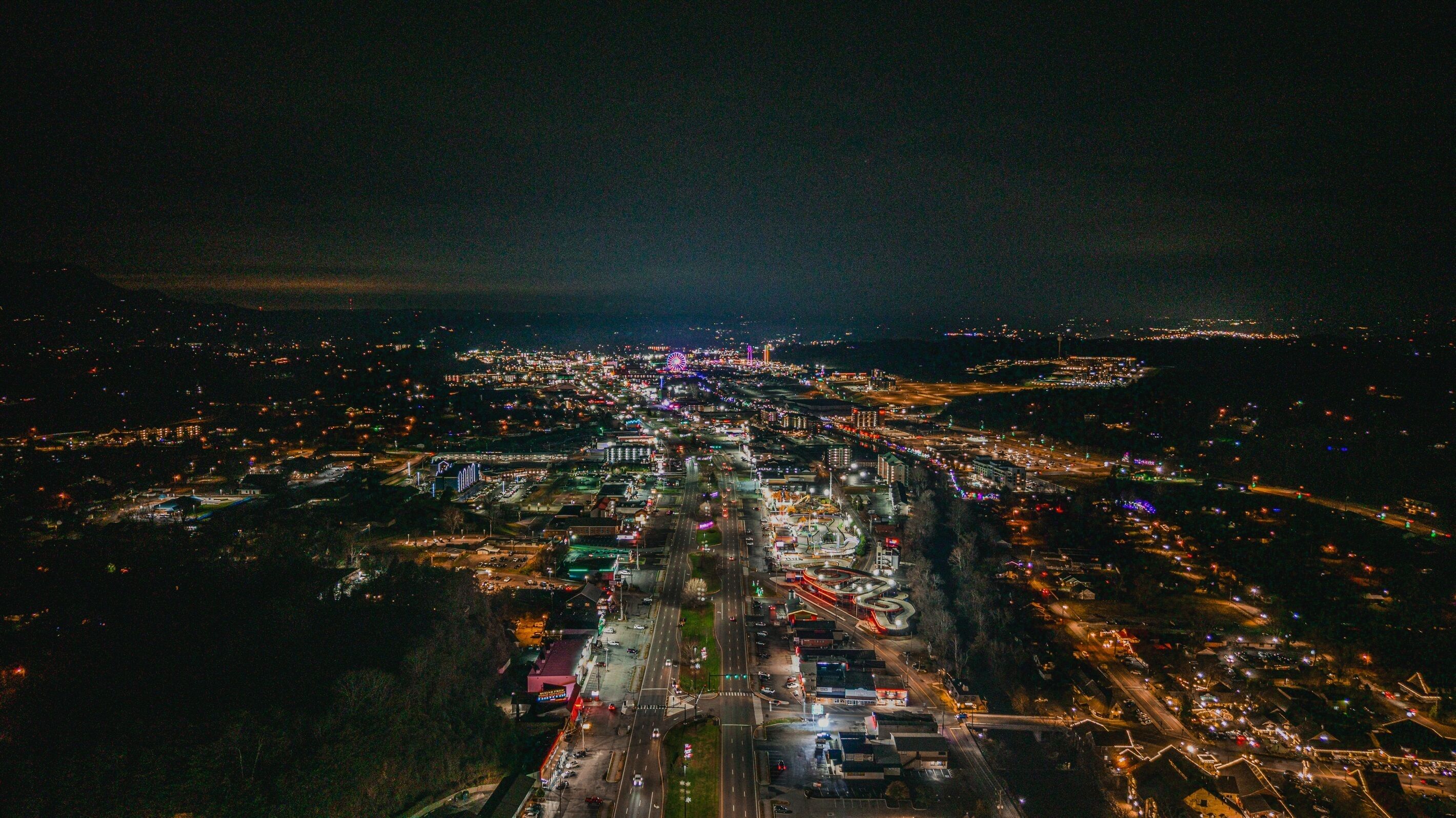 Luchtbeeld van een stad 's nachts, met verlichte straten en gebouwen.