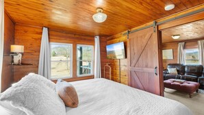 A wooden room with a bed, a TV, and a sliding door to a balcony.