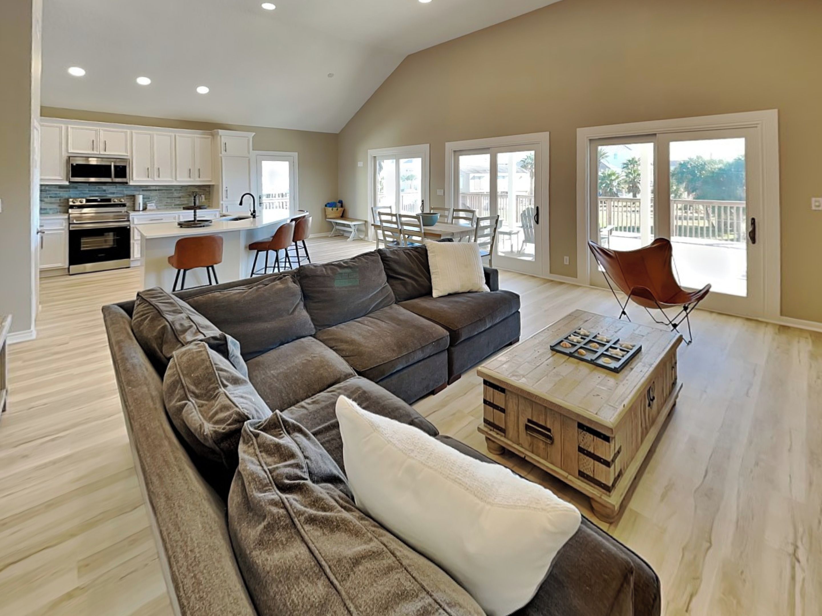 A spacious living room with a sectional sofa, a wooden coffee table, and a dining area with a table and chairs.