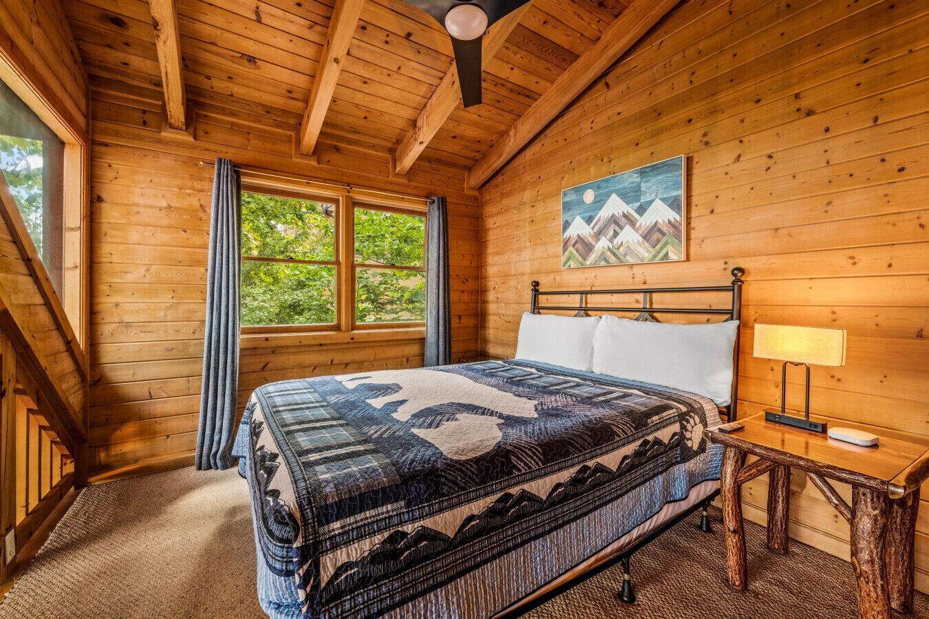 Une chambre à coucher dans un chalet en bois, avec un lit, une table de chevet, une lampe et un tableau représentant des montagnes.