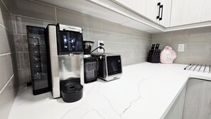 Uma cozinha com cafeteira, torradeira e uma toalha rosa.
