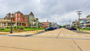 A street lined with Victorian-style houses, a crosswalk, and parked cars. - Walk to Downtown & Beach: Ocean Grove Apartment! (Ocean Grove)