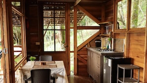 A wooden cabin interior with a dining area, kitchen, and seating. - Resurreeccion (San Francisco)