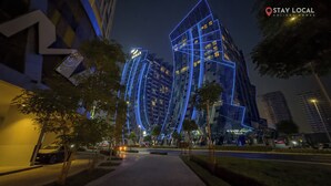 A modern building with illuminated blue lines, a clear sky, and a pathway with trees. - Blissful Sanctuary 1BR Balcony w/ Canal View in vibrant Downtown Dubai (Dubai)