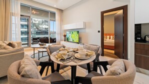 A modern living room with a round dining table, sofas, and a TV. - Blissful Sanctuary 1BR Balcony w/ Canal View in vibrant Downtown Dubai (Dubai)