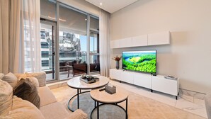 A modern living room with a large TV, a sofa, and a dining table. - Blissful Sanctuary 1BR Balcony w/ Canal View in vibrant Downtown Dubai (Dubai)