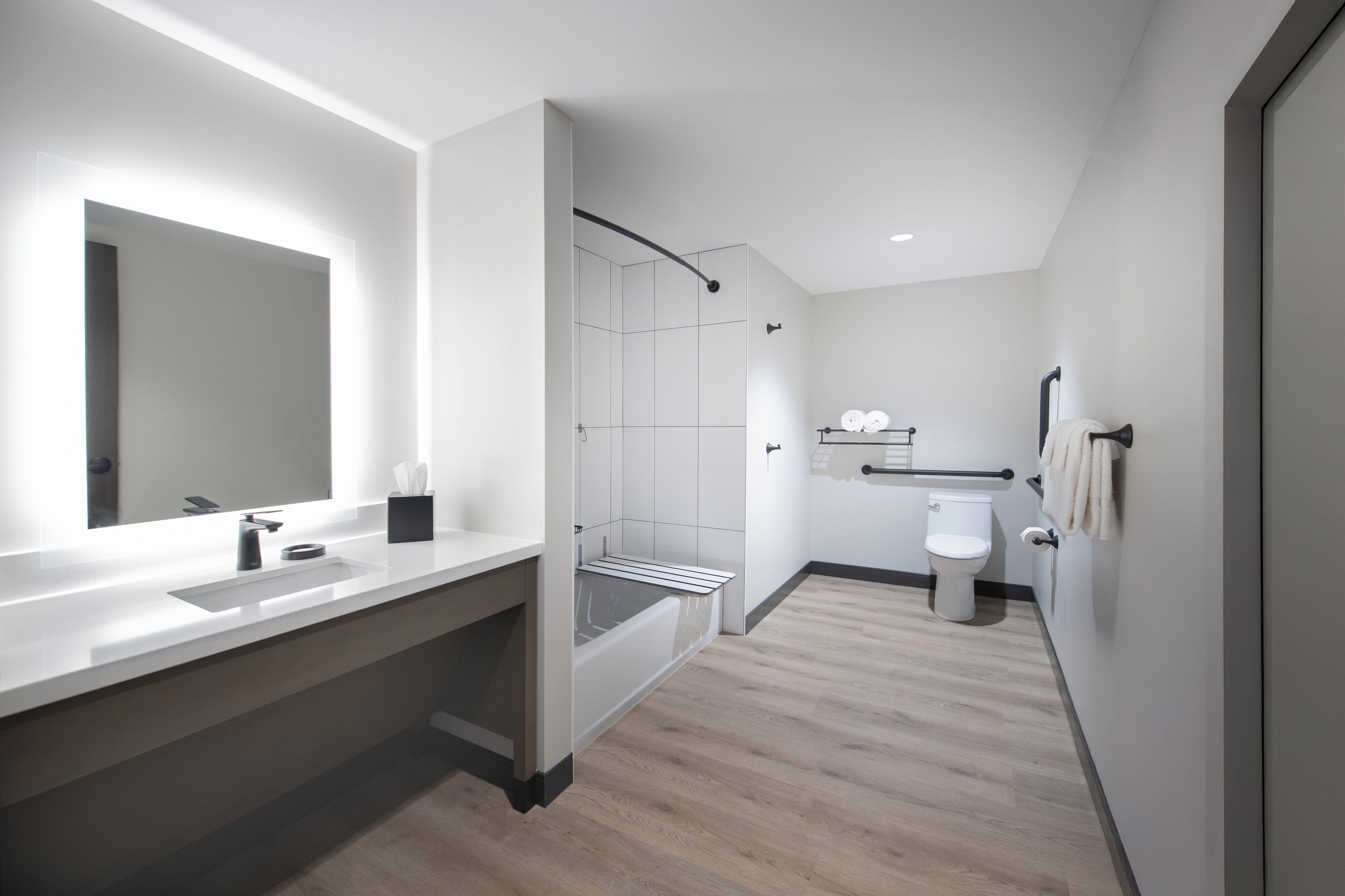 A modern bathroom with a large mirror, a shower, and a toilet.