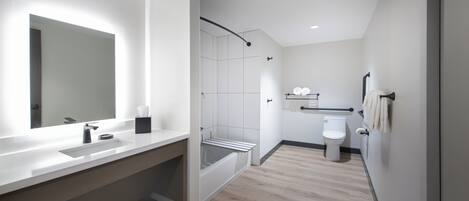 A modern bathroom with a large mirror, a shower, and a toilet.