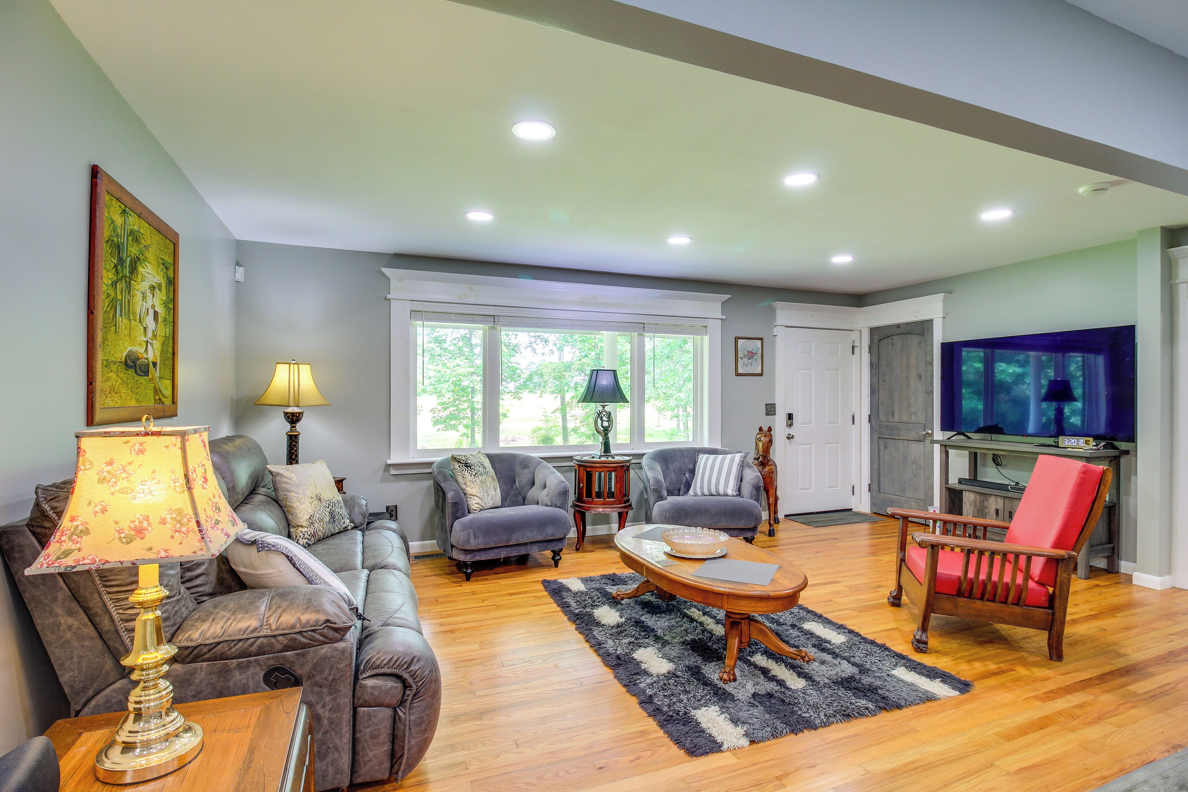 A living room with a sofa, two armchairs, a coffee table, and a TV.