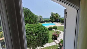 Blick auf einen Swimmingpool, umgeben von gepflegter Bepflanzung und einem Kiesweg.
