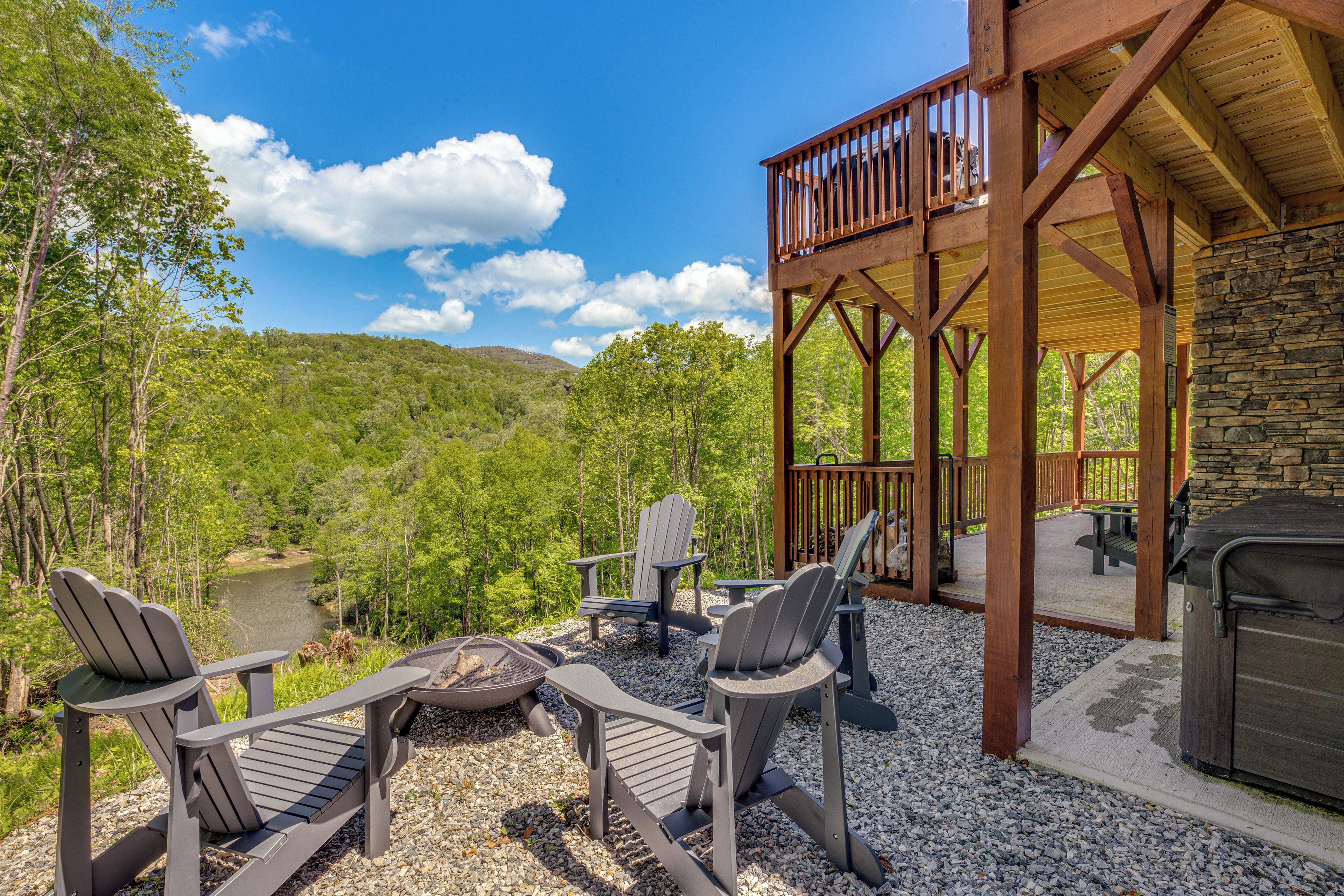 A wooden deck with Adirondack chairs, a fire pit, and a stone wall.