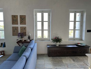 Un salon avec un canapé bleu, une console en bois foncé et une fenêtre aux cadres blancs.
