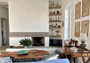 A living room with a fireplace, wooden shelves, a television, and various decorative items.