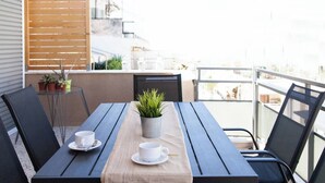A balcony with a wooden table, two chairs, and a potted plant.