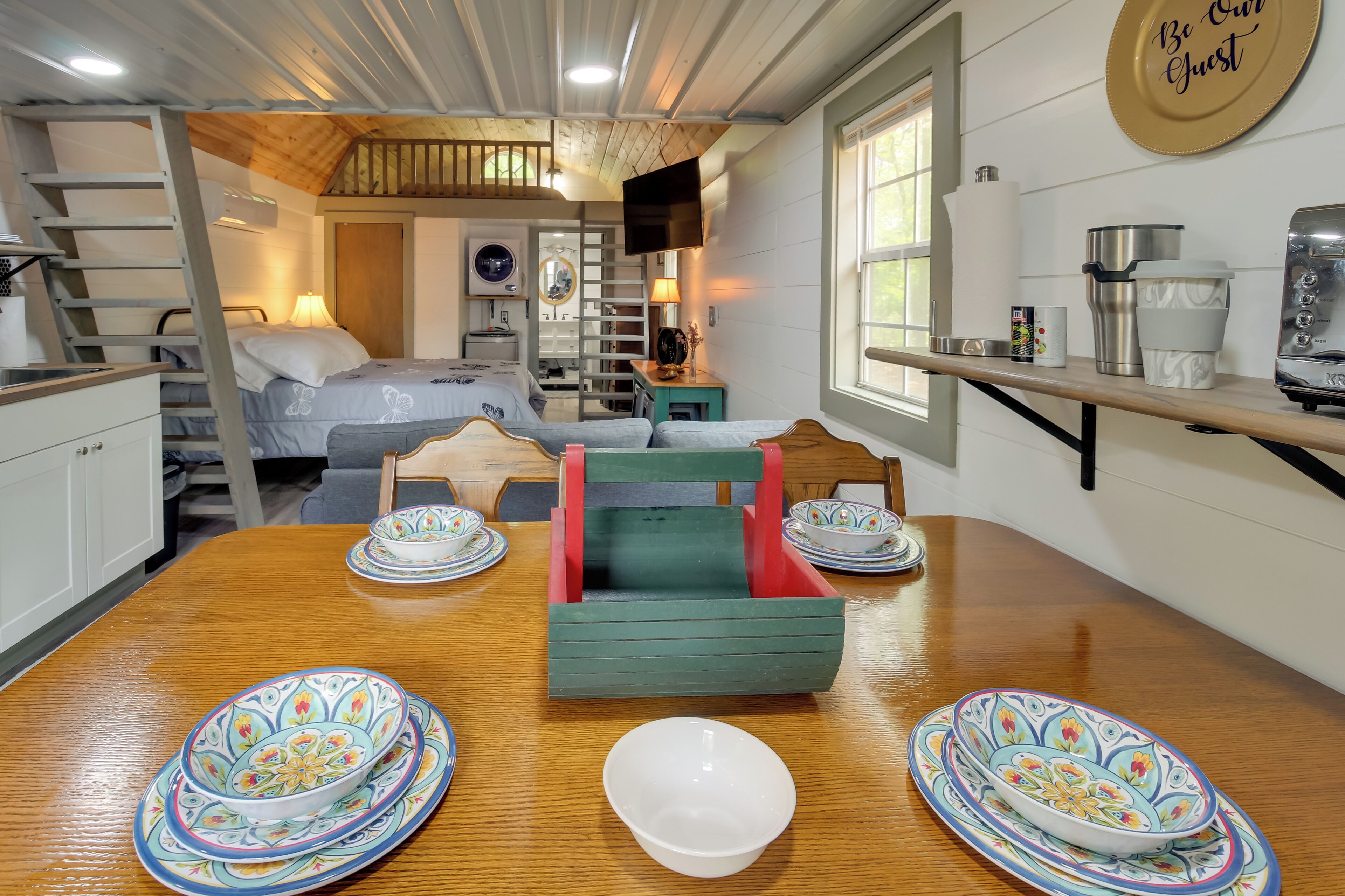 Een kleine hotelkamer met kitchenette, een eethoek met een houten tafel en een bed met uitzicht op de binnenplaats.