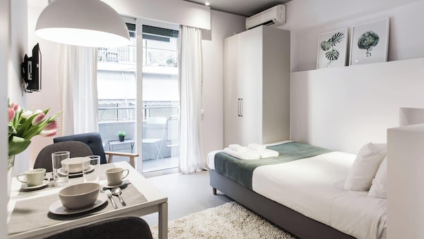 A modern bedroom with a bed, bedside table, and a view of the balcony.