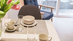 A dining table set with plates, bowls, and cups, a vase of tulips, and a chair.