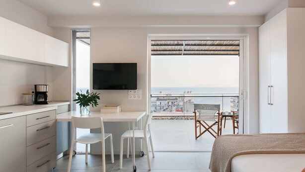 Una habitación de hotel moderna con balcón, zona de comedor y televisor.