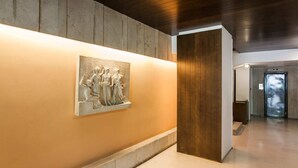 Un pasillo con un relieve de mármol, paneles de madera y un ascensor moderno.