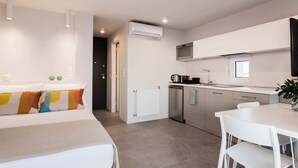 Una habitación de hotel moderna con cama, una kitchenette pequeña y un área de comedor.