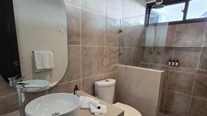 Un baño moderno con lavamanos redondo, inodoro y zona de ducha.