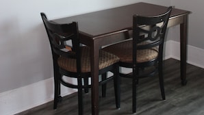 Un coin repas avec une table en bois et deux chaises, un tableau encadré au mur et un plancher de couleur claire.