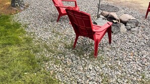 Une cabane en rondins avec une terrasse, un espace salon extérieur et un sol en gravier.