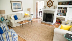 A living room with a fireplace, a bookshelf, and a striped sofa. - Inn at Haven Harbour (Rock Hall)