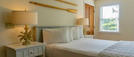 A bedroom with a bed, two nightstands, a lamp, a decorative piece, and a window with blinds.